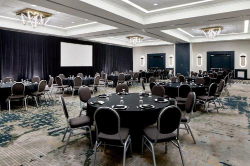 uma sala de conferências com mesas e cadeiras e um ecrã em Detroit Metro Airport Marriott em Romulus