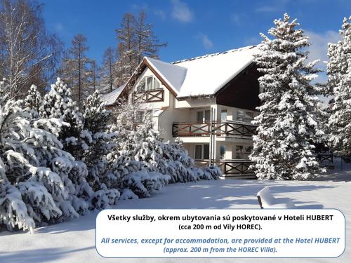 ein schneebedecktes Haus mit Bäumen in der Unterkunft Vila Horec - depandance hotela Hubert Vital Resort in Vysoké Tatry