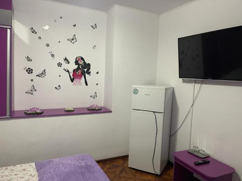 een kamer met een koelkast en een tv met vlinders aan de muur bij CAMERE de INCHIRIAT LA TUGUIATA in Buşteni