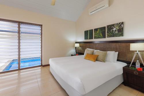 een slaapkamer met een groot wit bed en een raam bij Mangoes Resort in Port Vila