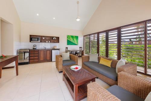 een woonkamer met banken en een tafel en een keuken bij Mangoes Resort in Port Vila