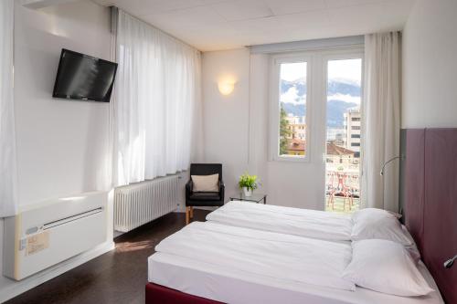 una camera con un letto bianco e una finestra di Hotel Rio Muralto a Locarno