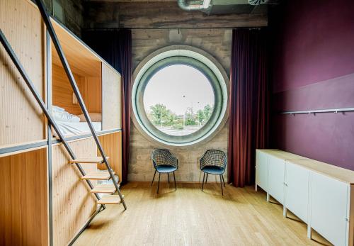 Zimmer mit 2 Stühlen und einem runden Fenster in der Unterkunft Silo Design & Boutique Hostel Basel in Basel