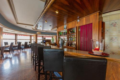 un restaurant avec un bar doté de chaises et de tables noires dans l'établissement Hotel Athmos, à La Chaux-de-Fonds