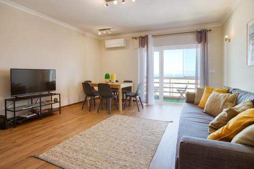 - un salon avec un canapé et une table avec une télévision dans l'établissement Ericeira Beach Apartment, à Ericeira