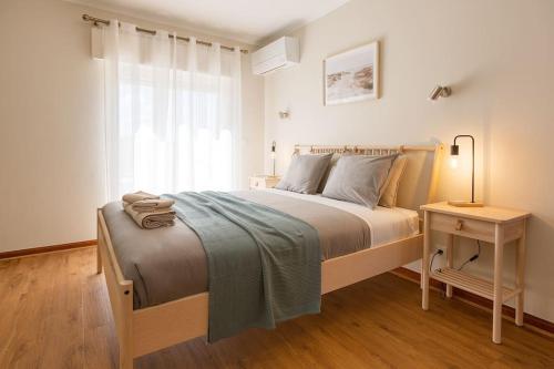 - une chambre avec un lit et une table avec une lampe dans l'établissement Ericeira Beach Apartment, à Ericeira