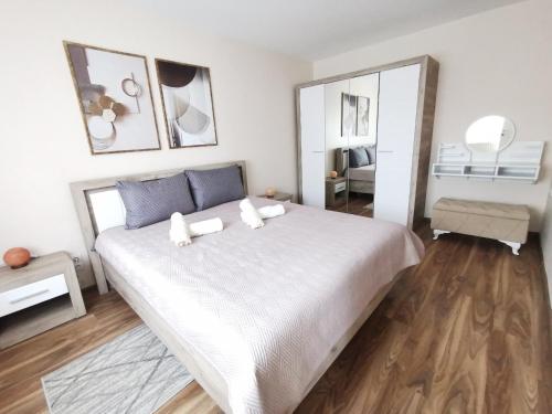 a bedroom with a large white bed and a mirror at Apartman Bonsai in Subotica