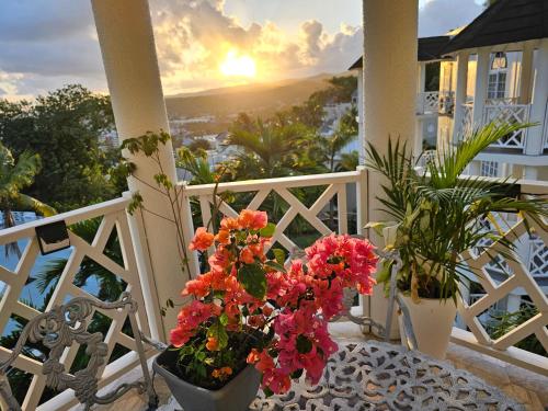 uma varanda com flores numa mesa com o pôr-do-sol em Blue Topaz em Ocho Rios