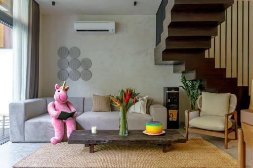 uma sala de estar com um bicho de peluche cor-de-rosa sentado num sofá em Sunny Cuddles em Canggu