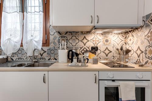 a kitchen with white cabinets and a sink at Nel cuore del rione del Drago in Pistoia