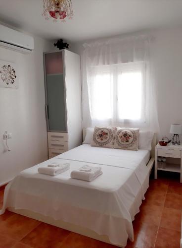 una camera da letto con un letto bianco e asciugamani di Habitación Avileña Tropical en Aguadulce a Almería