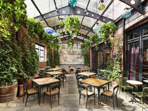 een restaurant met tafels, stoelen en planten bij The Ludlow Hotel in New York