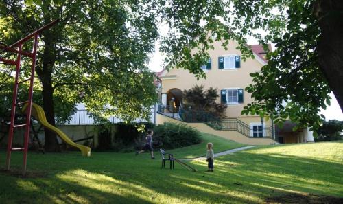 eine Familie spielt auf einem Hof mit Spielplatz in der Unterkunft Ferienhof Uhudler-Arkaden in Stegersbach