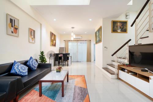 a living room with a black couch and a tv at AreeHouse 曼谷 300平方 獨棟別墅 家庭首選 近7-11 超市 MRT in Bangkok