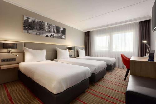 Ramada by Wyndham Amsterdam Airport Schiphol في باتهوفيدورب: غرفة فندقية بسريرين ومكتب