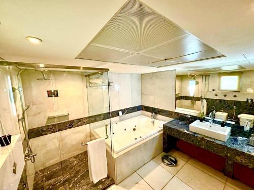 ein Badezimmer mit einer Dusche, einer Badewanne und einem Waschbecken in der Unterkunft King Suites Hotel in Beirut