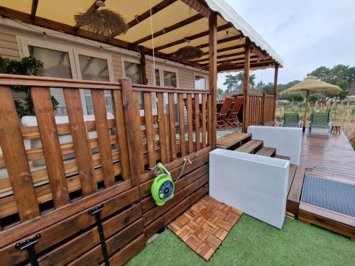 une terrasse en bois avec une pergola et un patio dans l'établissement Mobil home tout confort au Camping Les Viviers, Cap Ferret, à Claouey