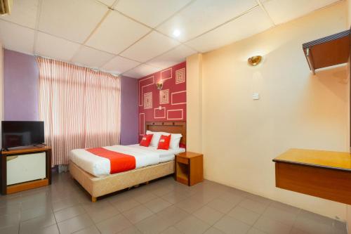 una camera d'albergo con letto e TV di OYO 90929 DJ Hotel a Lumut