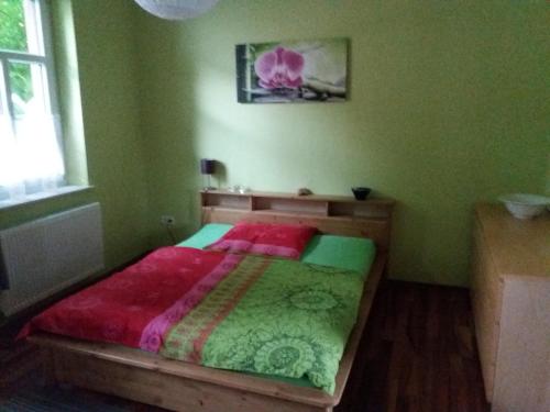 a green bedroom with a bed with a red comforter at Allsaitig Klang- und Seminarzentrum Selb in Selb