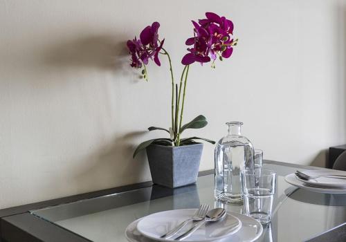 una mesa con un plato y un jarrón con flores púrpuras en Apartamento EL MIRADOR, recepción 24 h, piscina, wifi y parking interior, en Bormujos