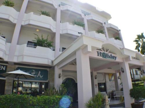 a large white building with a sign on it at Holiday Saipan Hotel in Saipan