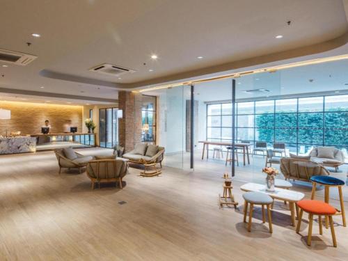 Clef Hotel Bangkok في بانكوك: لوبي فيه كراسي وطاولات في مبنى