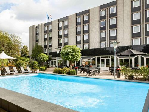 a hotel swimming pool in front of a building at Novotel Maastricht in Maastricht