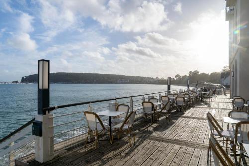 een pier met tafels en stoelen op het water bij Hôtel Morgat Le Grand Hôtel De La Mer in Crozon