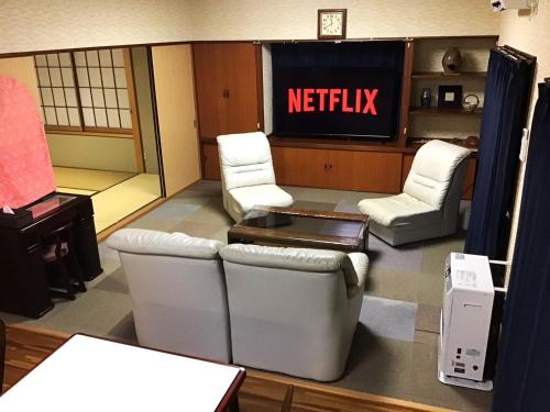 une salle d'attente avec des chaises blanches et un panneau netflix dans l'établissement Nikko World Heritage STAY【日光山内】一棟丸貸しの宿, à Nikkō