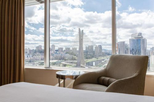 ein Schlafzimmer mit einem Stuhl vor einem großen Fenster in der Unterkunft Grand Hyatt São Paulo in São Paulo