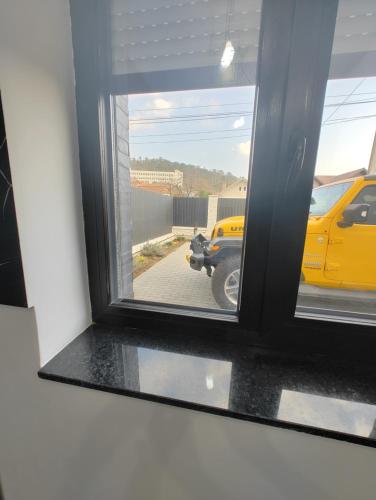 a window with a view of a yellow taxi at Black&White House in Ocna-Mureşului