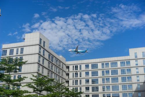 a plane is flying over a building at Guangzhou Baiyun Airport Yunzhi Hotel near Terminal One - Complimentary Shuttle Bus between hotel to Canton Fair Complex during Canton Fair in Guangzhou