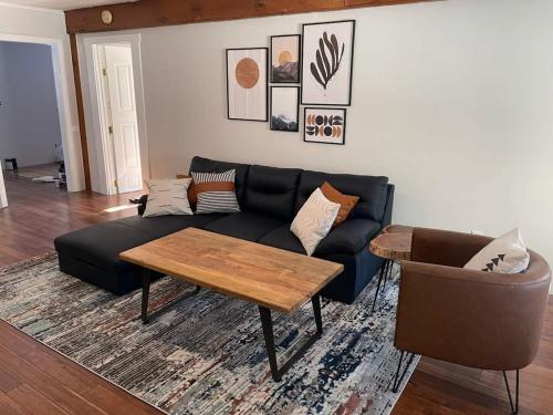 - un salon avec un canapé noir et une table dans l'établissement Modern & Cozy Getaway House near Conway lake - Pet Friendly, à Conway