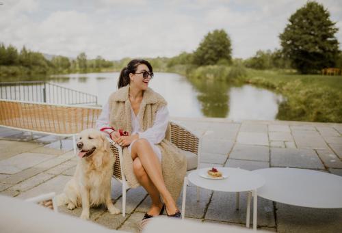 Una donna seduta su una panchina con un cane di Pałac Pakoszów Schlosshotel Wernersdorf a Jelenia Góra