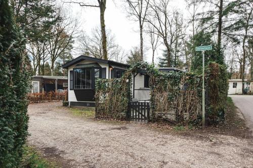 a small house with a gate on the side of a road at Chalet op familiepark Veluws Hof op de Hoge Veluwe in Hoenderloo