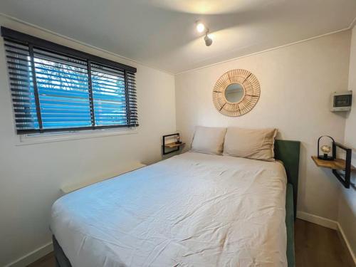 a white bed in a bedroom with a window at Chalet op familiepark Veluws Hof op de Hoge Veluwe in Hoenderloo