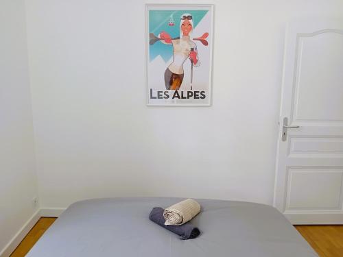 einen Hut auf einem Bett in einem Zimmer mit einem Poster in der Unterkunft 102 - Appart rénové avec grand salon et 1 chambre - Tram et Clinique Mutualiste à 1 min in Grenoble