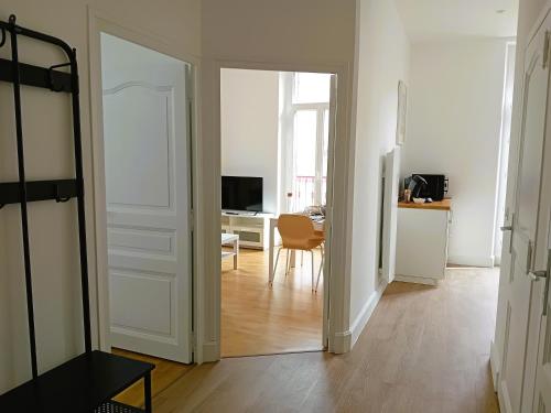 einen Flur mit einer Tür zu einem Zimmer mit einem Tisch in der Unterkunft 102 - Appart rénové avec grand salon et 1 chambre - Tram et Clinique Mutualiste à 1 min in Grenoble