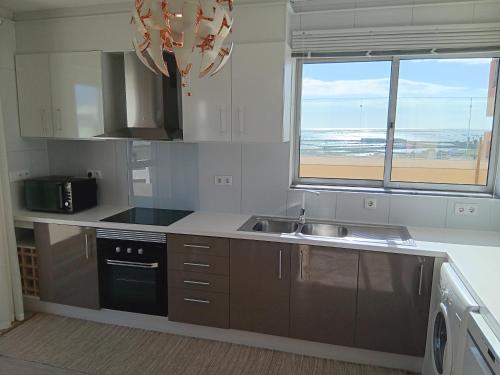 uma cozinha com um lavatório e uma janela com a praia em 7stars Apartment em Faro