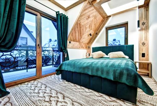 a bedroom with a green bed and a large window at Domki pod Grapą JAKUZZI & DELUXE & Willa pod Grapą in Poronin