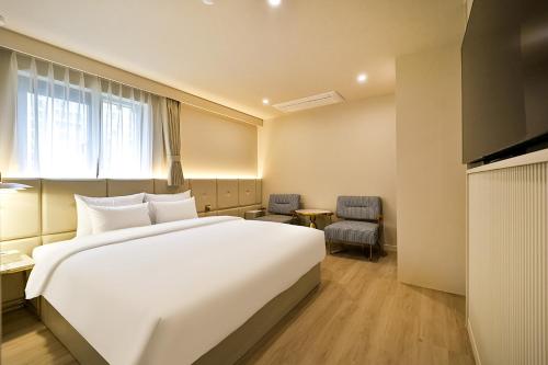 a hotel room with a large white bed and a window at Denbasta Hotel Daeyeon in Busan