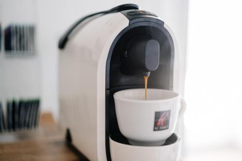 una macchinetta del caffè che versa il caffè in una tazza di GästeHaus am Flughafen Düsseldorf a Dusseldorf