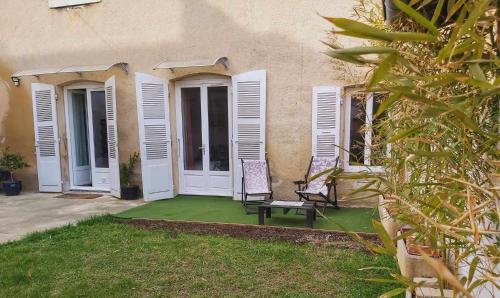 una casa con dos sillas sentadas en un patio en L’Oasis Fleuri, en Bourg-de-Péage