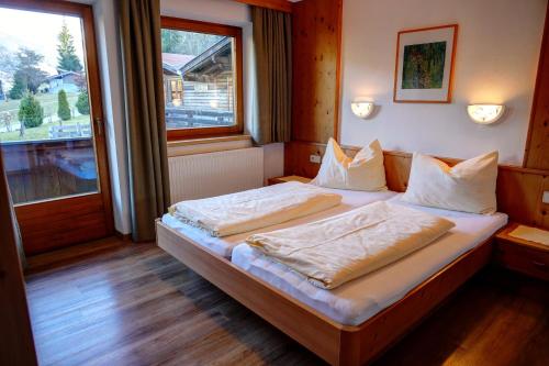 1 dormitorio con 1 cama con sábanas blancas y ventana en Ferienhotel Iris, en Auffach