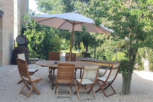 een tafel en stoelen met een paraplu en een klok bij MAISON SYLVAIN in Tournus