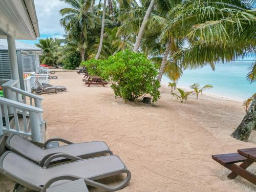 una spiaggia con sedie e tavoli su una spiaggia di Bella Beach Bungalows a Rarotonga