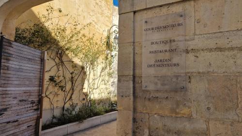 una pared de piedra con una señal en el lateral de un edificio en La Cour Des Senteurs / F2 Château de Versailles, en Versalles