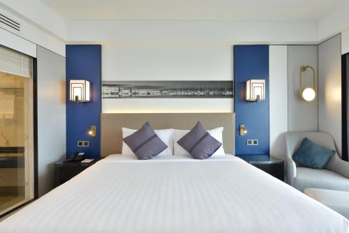 een slaapkamer met een groot wit bed met blauwe muren bij D Varee Jomtien Beach, Pattaya in Jomtien Beach