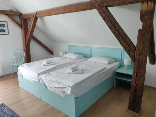 un letto blu in una camera con travi in legno di Hotel Celerin a Telč