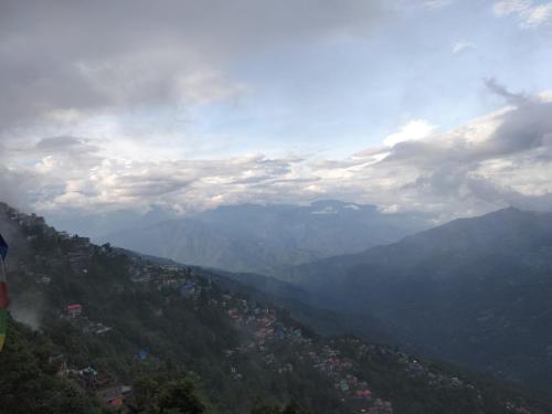 uma vista para um vale com montanhas e uma cidade em Sunrise Homestay em Darjeeling